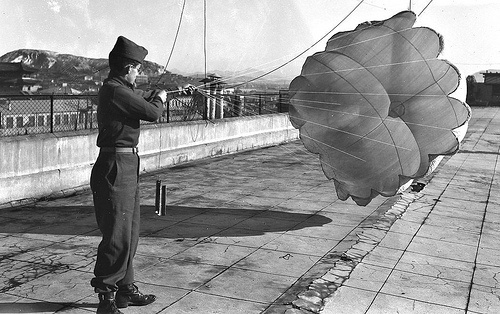 photo image of One of the guys in our unit found the Japanese parachute. We had fun playing with it on the roof of our quarters in Seoul where we lived in a former school building near the East Gate. I think this is looking southeast. Does anyone recognize the location.? Roland Oxton, a Boston Post photographer in civilian life, found the chute and took the picture of me with a Speed Graphic 